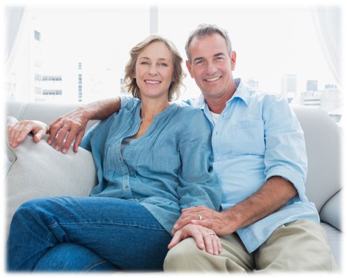 A man and woman sitting on the couch smiling.