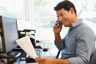 A man sitting at his desk on the phone